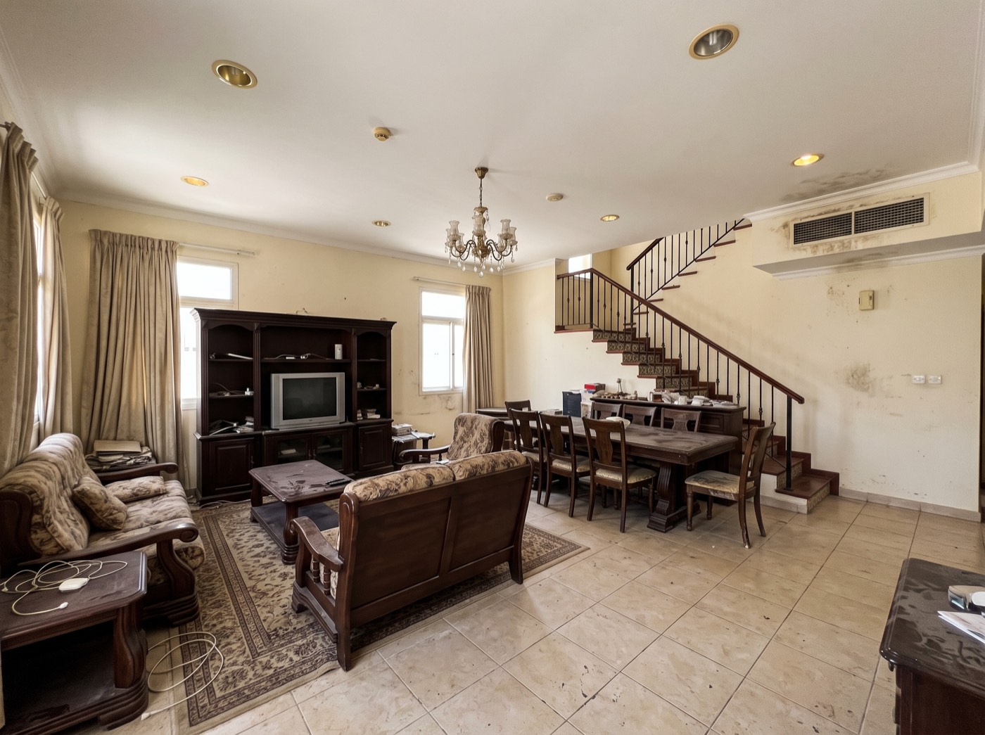 Villa living room before renovation — dated tiles and heavy furniture